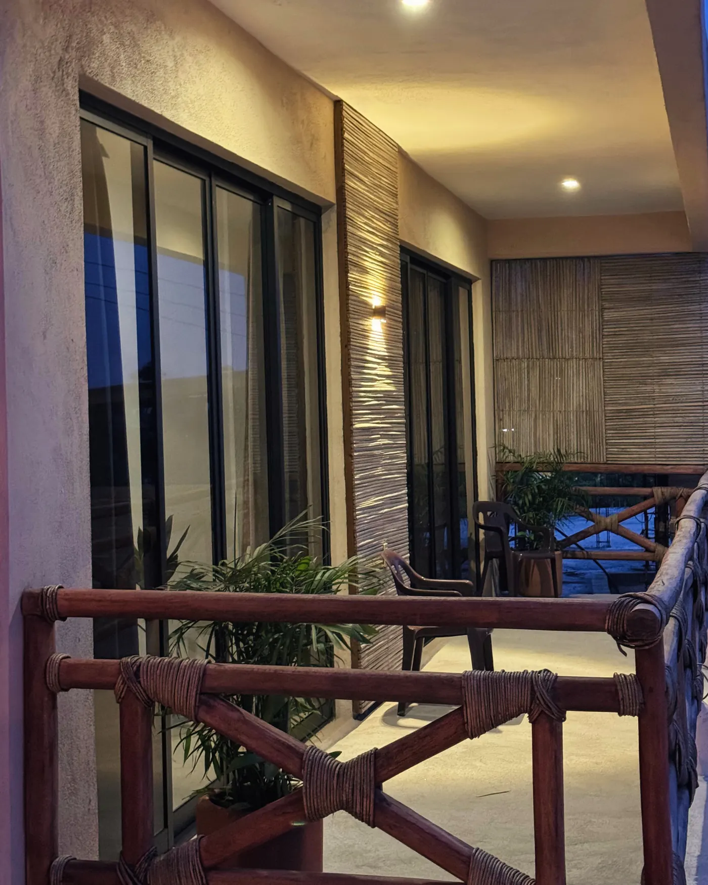 Balcón iluminado al anochecer con barandal de madera amarrada