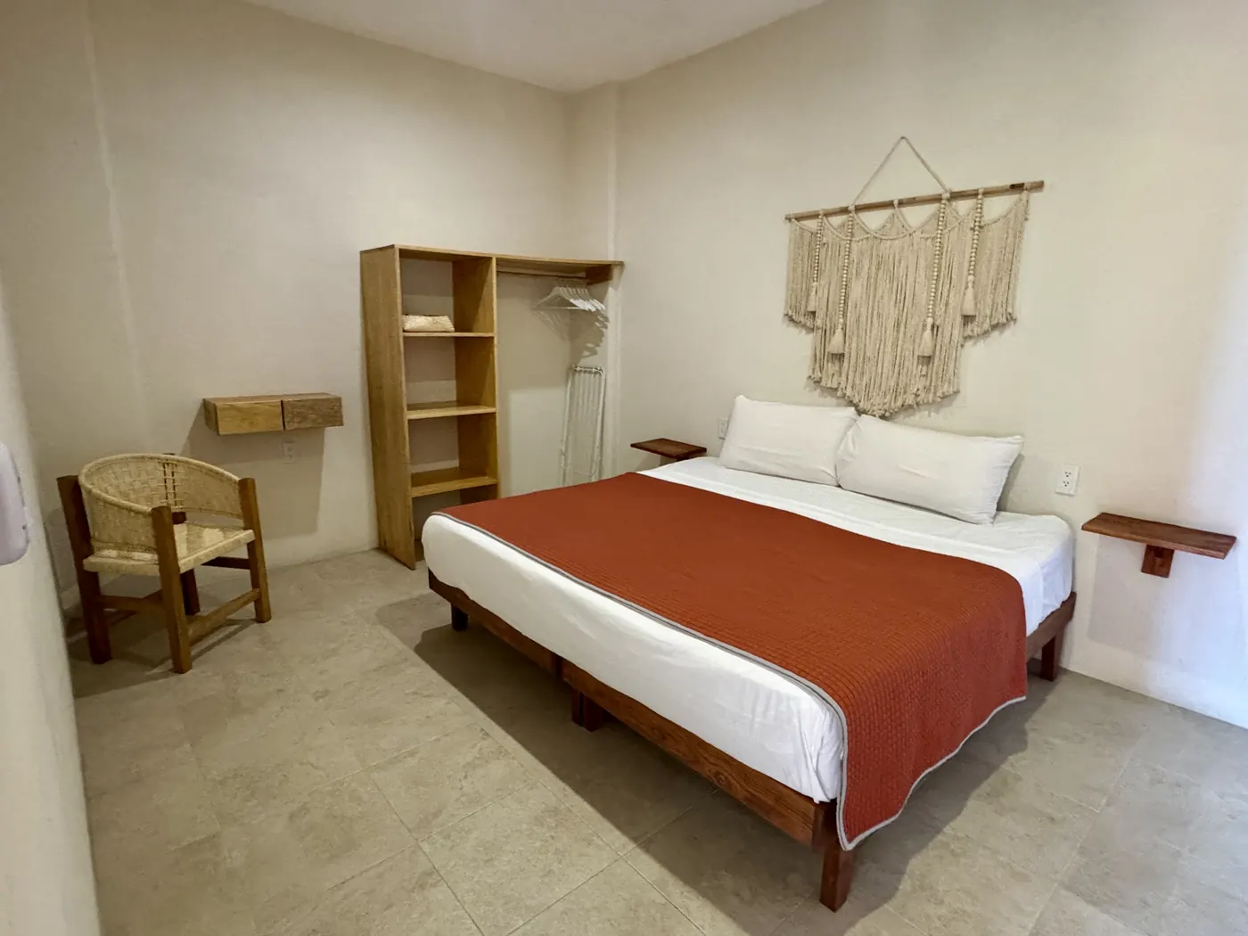 Recámara con cama King, colcha terracota y armario de madera