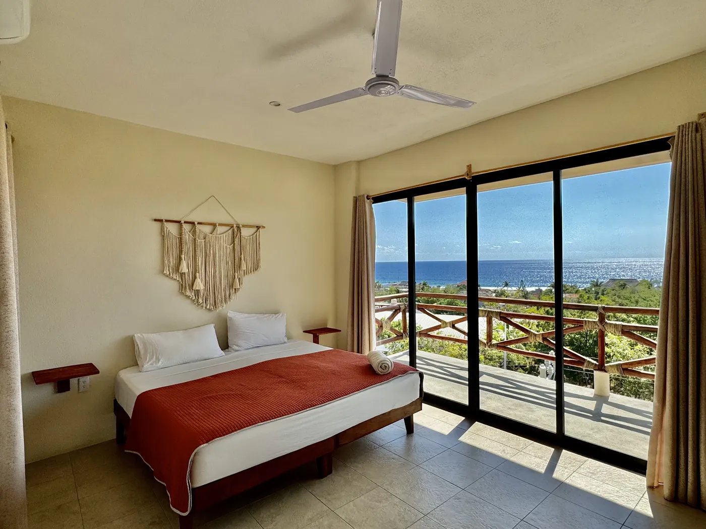 Recámara con cama King y ventanal de piso a techo con vista al océano