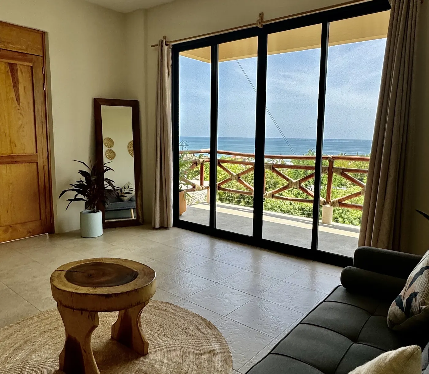 Sala con mesa de madera frente a un ventanal con vista al océano