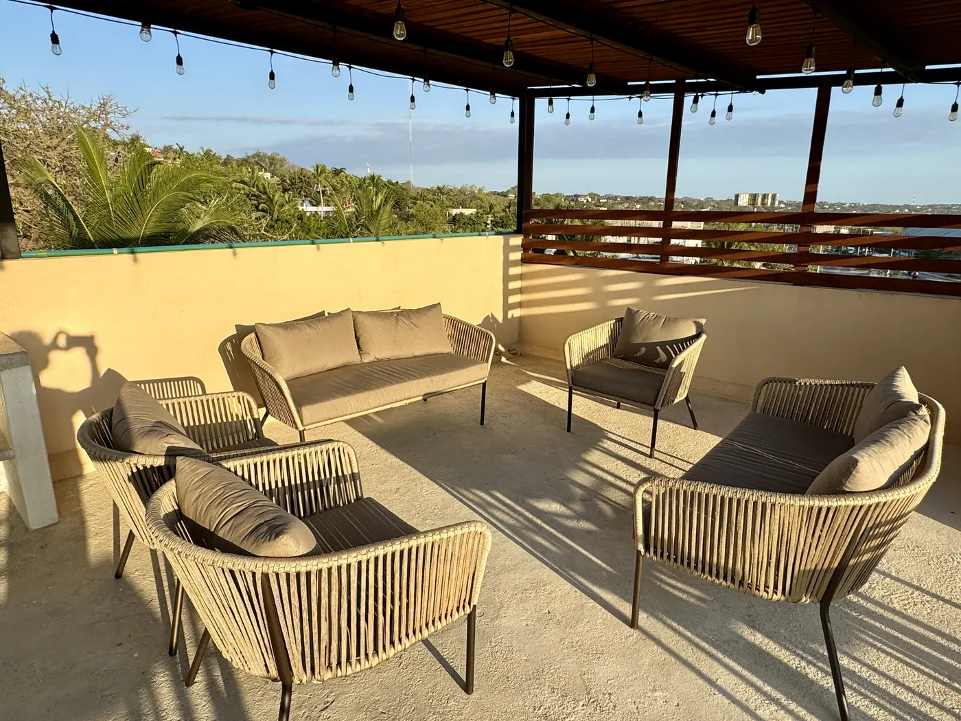 Salas exteriores tejidas bajo una pérgola con series de luces